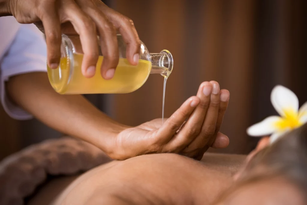 Un huile se versant dans la main d'une masseuse.