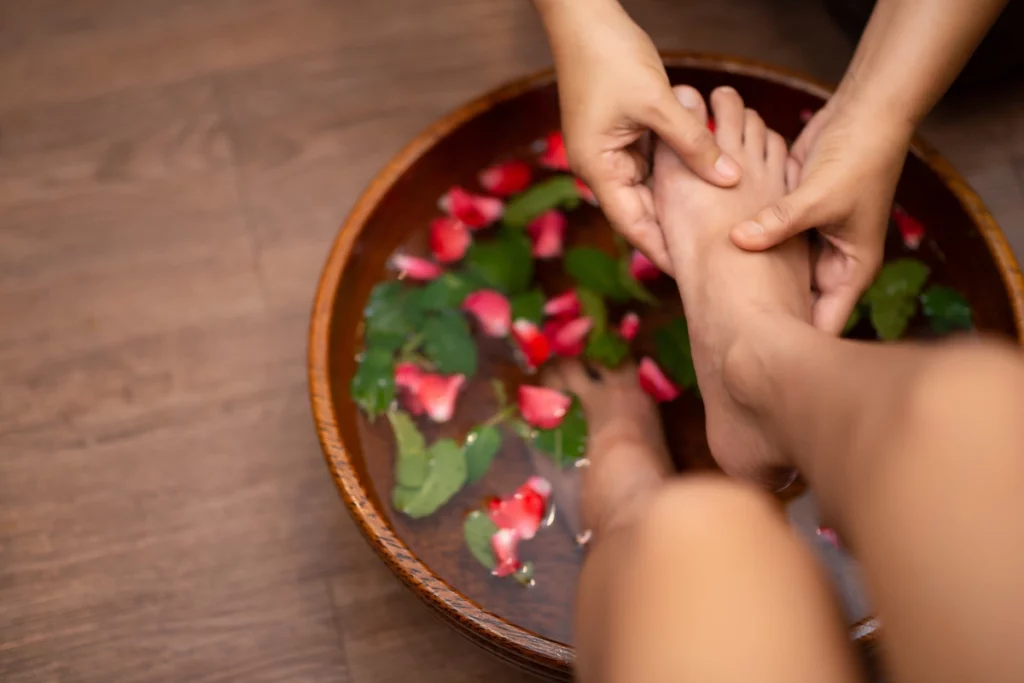 Massage des pieds au dessus d'une bassine deau et de fleurs.