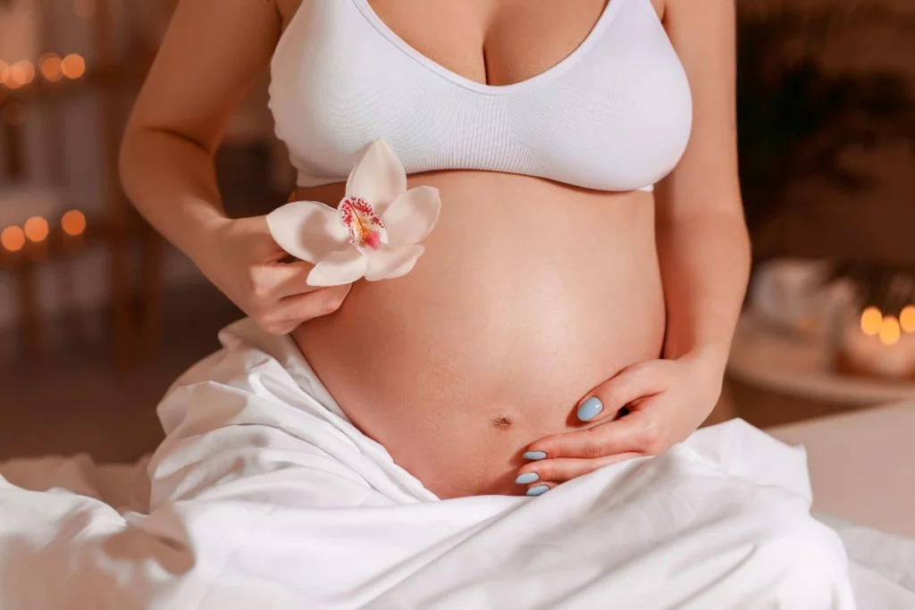 Femme enceinte avec une fleur dans la main.